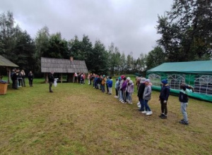 Duża grupa dzieci stoi w szeregu na łące na tle zielonego namiotu