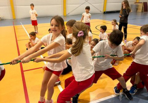 Uczniowie w hali sportowej przeciągają linę.