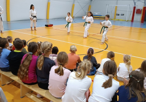 Trójka uczniów pokazuje swoje umiejętności podczas zajęć karate.