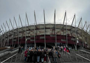 Uczniowie pozują do zdjęcia na tle Stadionu Narodowego.