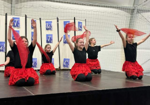 Występ choreograficzny jednej z grup - dziewczęta w czarno-czerwonych strojach.