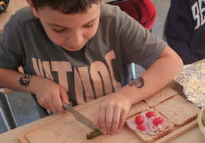Chłopiec kroi ogórka w plasterki.