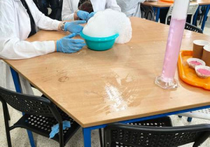 Uczniowie podczas warsztatów wytwarzają suchą pianę z użyciem suchego lodu.