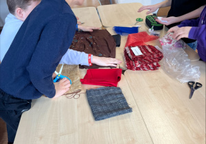Uczniowie poznają różne rodzaje tkanin.