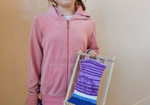 Uczennica prezentuje swój wyrób tkacki.