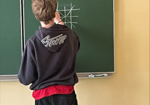 Chłopiec rozwiązuje zadanie na tablicy.