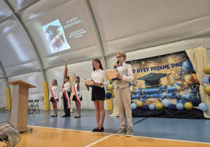 Uczniowie podczas zakonczenia roku szkolnego, w tle poczet sztandarowy.