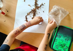 Wyklejanie litery "J" z pokruszonych suchych liści.