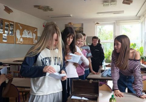 Uczniowie stoją w rządku z przygotowanymi listami.