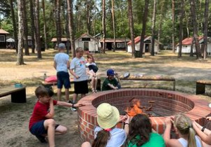 Dzieci pieką kiełbaski na ognisku